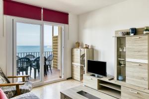 a living room with a television and a balcony at Riells Platja in L'Escala