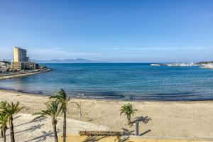 a beach with palm trees and the ocean at Riells Platja in L'Escala