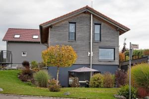 a gray house with a tree in the front yard at Kathi´s Allgäuliebe in Weitnau