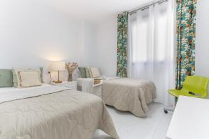 a bedroom with two beds and a chair and a window at Retama in Adeje