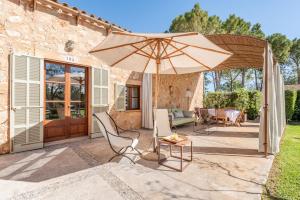 a patio with an umbrella and chairs and a table at Es Lledoner 2 in Islas Baleares