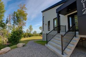 a tiny house with a front porch and stairs at O Vitre Spa - Relax with St-Lawrence Views in Les Éboulements