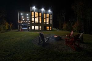 a house with a fire pit in the yard at night at O Vitre Spa - Relax with St-Lawrence Views in Les Éboulements +32 photos
