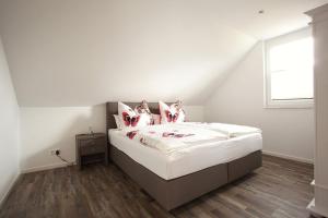 a bedroom with a bed with white sheets and pink pillows at Ferienhaus Am Rösslewald in Breitnau
