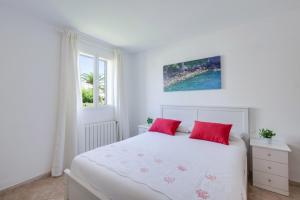 a white bedroom with red pillows on a bed at Villa Loli in Alcudia +22 photos