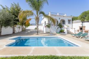a pool in front of a house with a palm tree at Cortijo Encarni in Frigiliana