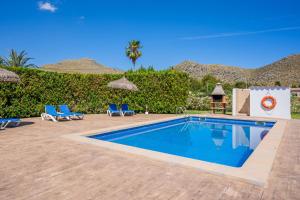 a swimming pool with two blue lounge chairs next to a resort at Villa Can Serra in Port de Pollensa