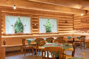 a dining room with tables and chairs and windows at Agritur Cazzuffi in Peio