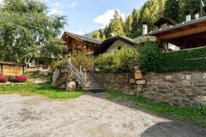 a house with a stone wall and a stone staircase at Agritur Cazzuffi in Peio