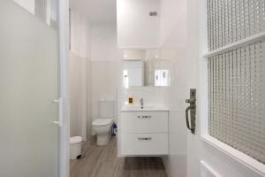 a white bathroom with a toilet and a sink at T4 Furadouro with sea view in Ovar +25 photos