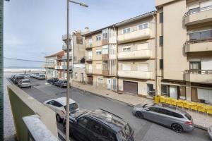a street with cars parked in front of a building at T4 Furadouro with sea view in Ovar
