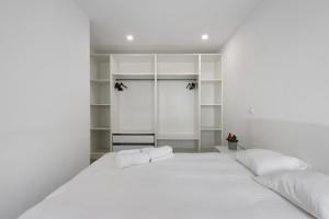 a bedroom with a large white bed and shelves at T4 Furadouro with sea view in Ovar