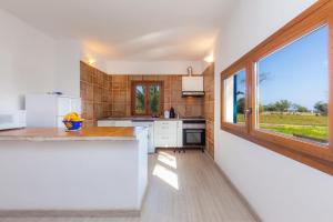 a kitchen with white counters and a large window at Sa Casona in Portocolom