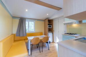 a kitchen with a table and chairs in a room at Mobilhome Calvi 15 Climatisé in Bouzic