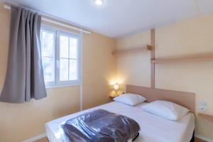 a bedroom with a large bed with a window at Mobilhome Calvi 15 Climatisé in Bouzic +15 photos