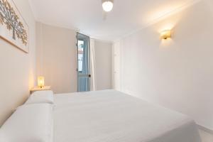 a white bedroom with a white bed and a window at Ático Bellavista B - Alcalá in Guía de Isora