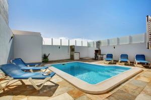 a patio with a swimming pool and blue chairs at Preciosa Casa En Lanzarote in Tahiche