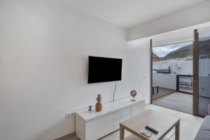 a living room with a tv on a white wall at Sun and serenity pool wifi in Puerto Rico de Gran Canaria