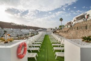 a row of white chairs on the roof of a resort at Sun and serenity pool wifi in Puerto Rico de Gran Canaria