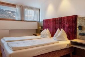 a hotel room with a large bed with a red headboard at Haus Rosengarten Apt D in Terlano