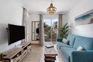 a living room with a blue couch and a tv at Casa Verdemar in Corralejo