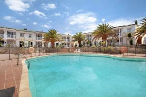 a large swimming pool with palm trees and buildings at Casa Verdemar in Corralejo