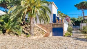 a palm tree next to a house with a blue garage at Costacabana - Casa Adora in Tossa de Mar