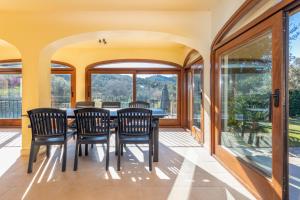 a dining room with a table and chairs and windows at Villa Rosa in Calonge