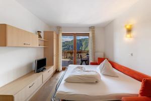 a bedroom with a bed and a tv and a balcony at Obertrisaierhof Wohnung 2 in Fie allo Sciliar