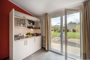 a kitchen with white cabinets and a sliding glass door at Appartamento Monolocale Rebi in Imperia