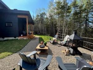 a backyard with chairs and a grill and a house at Chalet Le Select - Private Spa with River View in Les Éboulements