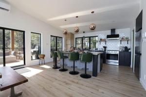 a kitchen with a large island with green bar stools at Chalet Le Select - Private Spa with River View in Les Éboulements