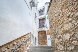 an alley with a wooden door in a stone building at El racó de les escales in Tivissa