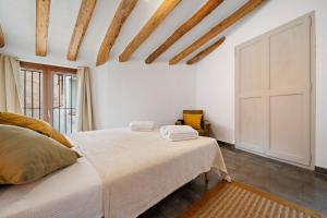 a white bedroom with a bed and wooden ceilings at El racó de les escales in Tivissa