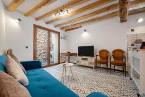 a living room with a blue couch and a tv at El racó de les escales in Tivissa