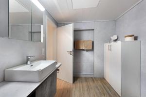 a white bathroom with a sink and a mirror at Haus Birkenösch in Aach-Linz +10 photos