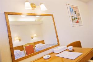 einen Spiegel auf einem Holzschreibtisch mit einem Tisch und einem Schreibtisch in der Unterkunft New Royal Hotel Shimanto in Shimanto