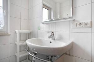 a white bathroom with a sink and a window at Ilse - Ferienwohnungen Zinnowitz in Zinnowitz +12 photos
