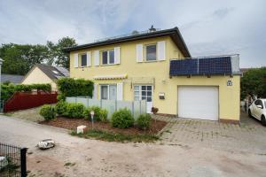 a yellow house with solar panels on the roof at Ilse - Ferienwohnungen Zinnowitz in Zinnowitz