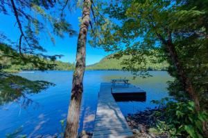 a dock with a picnic table on a lake at Luft Skift Spa - Waterfront & Private Spa in Lac-aux-Sables