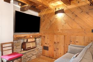 a living room with a tv on a wooden wall at Lo Pailler de Mamma e Pappa in Valsavarenche