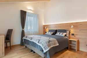 a bedroom with a bed and a chair and a window at Alpen Blumen in San Lorenzo in Banale