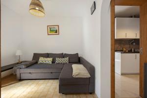 a living room with a gray couch and a kitchen at Casa Vitorino in Sagres +5 photos