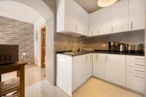 a kitchen with white cabinets and a brick wall at Casa Vitorino in Sagres