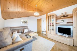 a living room with a couch and a television at Eichernhof Apartment Apfelblüte in Verano