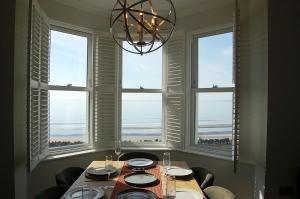 a table with chairs and a chandelier in a room with windows at Morwendon House with Sea View in Llanaber