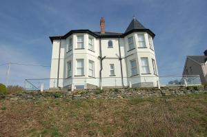 a large white house on top of a hill at Morwendon House with Sea View in Llanaber