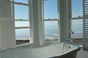a white bath tub in a room with windows at Morwendon House with Sea View in Llanaber +80 photos