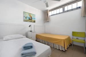 a bedroom with two beds and a yellow chair at Casa Médano 17 in Granadilla de Abona