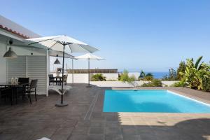 a villa with a swimming pool and a table and an umbrella at Villa Tino- Casa M in Los Llanos de Aridane